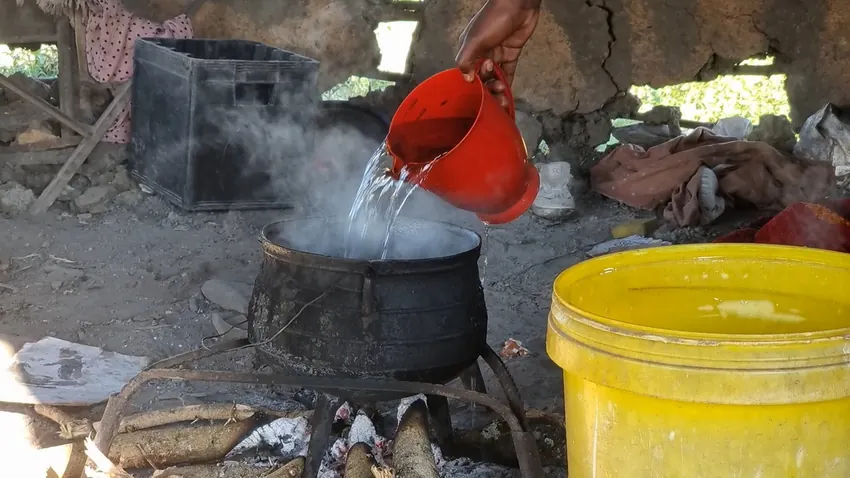 Water being boiled in a pot over a wood fire