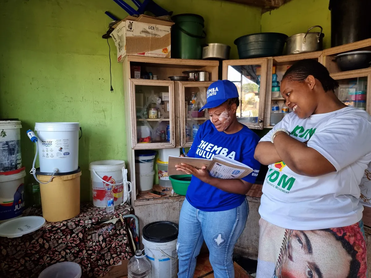 PureFlow Amanzi staff conducting a household monitoring visit and discussing filter use with a resident